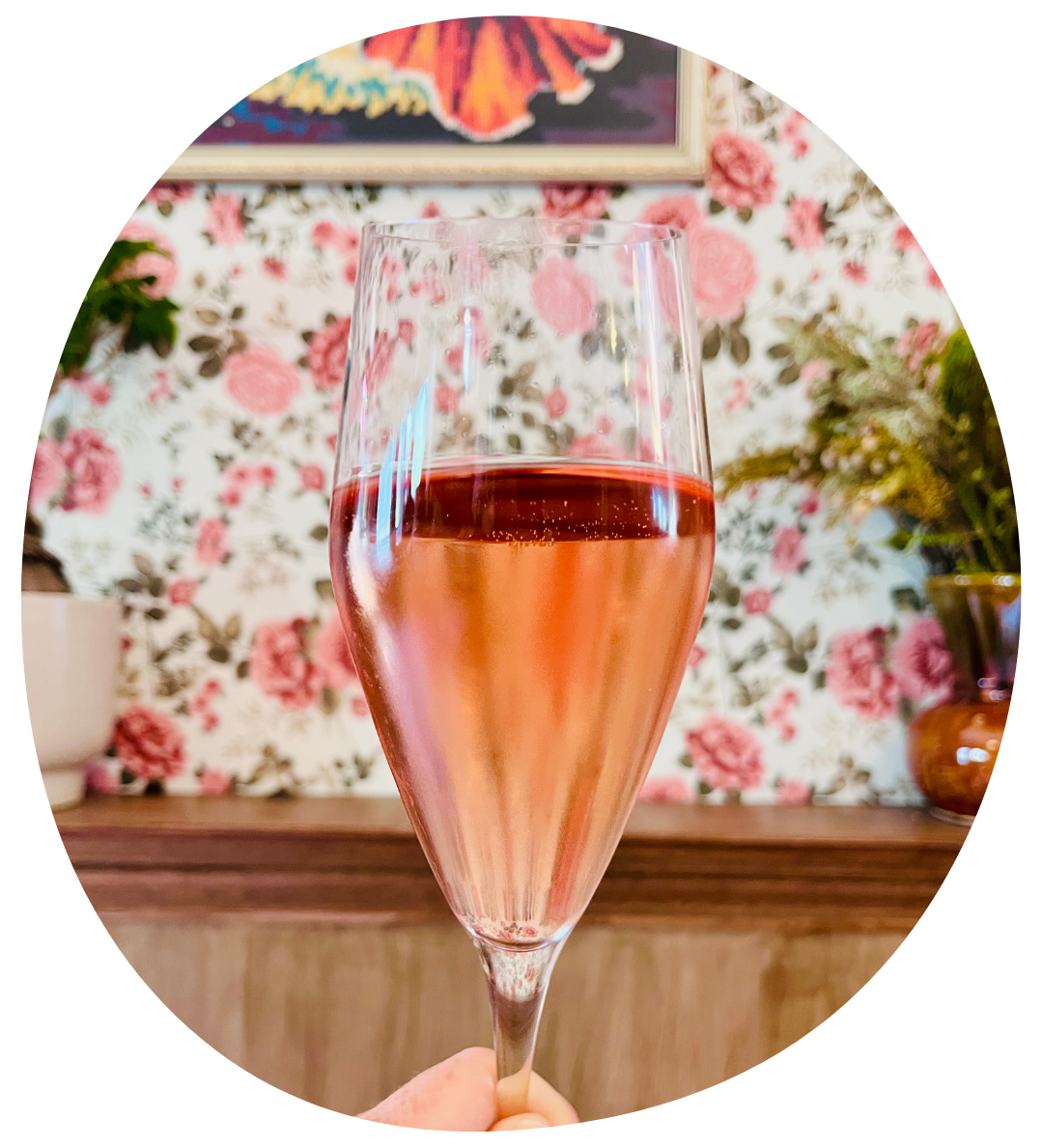A glass of Graham Beck Rose with a floral wallpaper background.